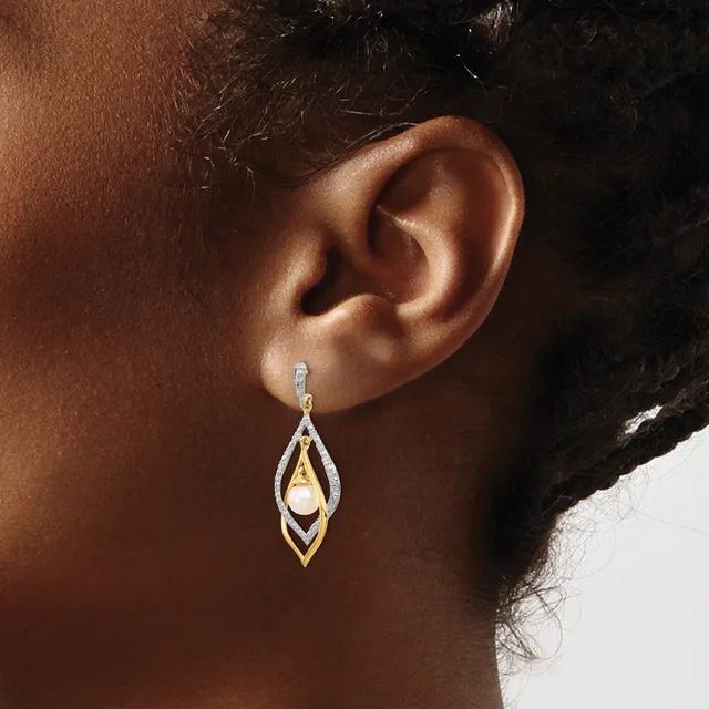 A teardrop-shaped drop earring with nested geometric frames in silver and gold tones, featuring a pearl, displayed on a model's ear.