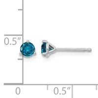 A pair of silver stud earrings with round blue topaz stones in three-prong settings, shown at actual size on a measurement scale.