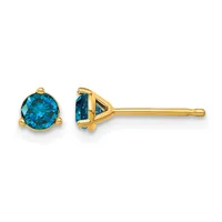 Pair of blue topaz stud earrings with three-prong settings in yellow gold, shown from front and side views.