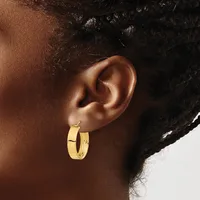 A woman wearing a gold hoop earring in her earlobe, shown in profile against a white background.