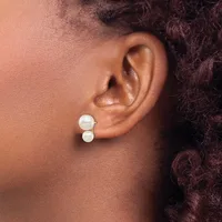 A person wearing two white pearl stud earrings in their lower earlobe piercing, shown in profile view.