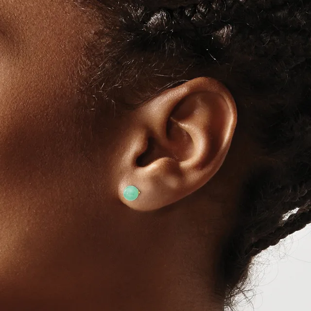 A small round turquoise stud earring worn in the earlobe of a person with brown skin and dark hair.