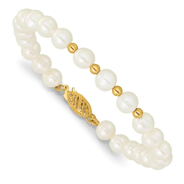 A beaded bracelet with large cream-colored round pearls separated by smaller gold-toned spherical beads, featuring a decorative gold-toned clasp with an engraved leaf design.
