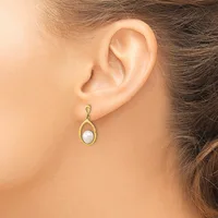 A woman wearing a gold teardrop-shaped earring with a white pearl in the center, shown from the side view of her ear and neck.