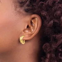 A person wearing a gold crescent-shaped hoop earring with a textured surface, shown in profile view against their ear and shoulder.