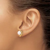 A person wearing a gold curved earring with a white pearl stud, shown from the side profile of their ear and neck.