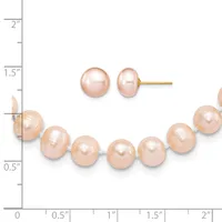 A peach-colored pearl bracelet and matching stud earrings displayed against a ruler showing measurements up to two inches.