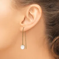 A person wearing a long threader earring with a thin chain and a small white round pendant hanging from the earlobe.