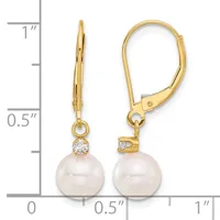 Gold lever-back earrings with round white pearls suspended below small diamond accents, displayed against a measurement ruler.