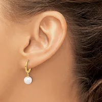 A person wearing a gold hoop earring with a white pearl pendant hanging from it, shown from the side view of their ear.