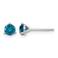 A pair of round brilliant-cut blue topaz stud earrings in white metal, shown from front and side views displaying the three-prong basket settings and post backs.