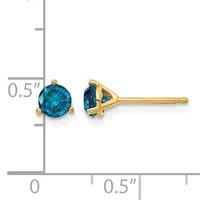 A pair of gold stud earrings with round blue gemstones displayed next to a ruler showing approximately half-inch size.