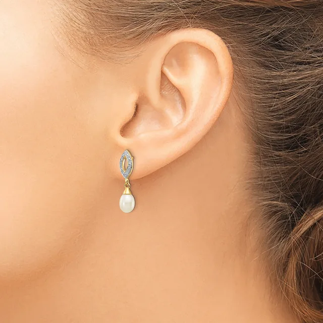 A person wearing a dangling earring with a blue oval gemstone top and a white pearl drop, shown from the side against their ear and neck.