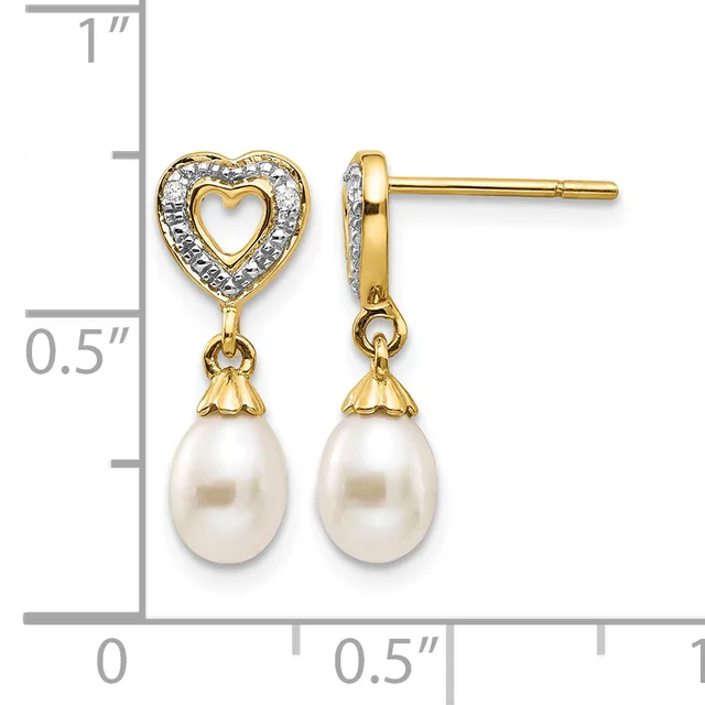 Gold-tone heart stud earrings with diamond accents and dangling white pearl drops, shown against a measurement scale.