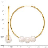 Gold-toned bangle bracelet with three white pearls at the bottom, shown open and displayed against a ruler measuring approximately 2.5 inches in height.