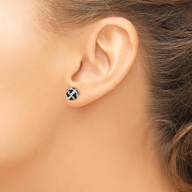 A small round stud earring with a geometric cross or X pattern in black and white sits on the earlobe of a person shown from the side.