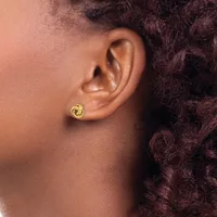 A person wearing a small gold twisted hoop earring in their earlobe, shown in profile against their neck and curly dark hair.