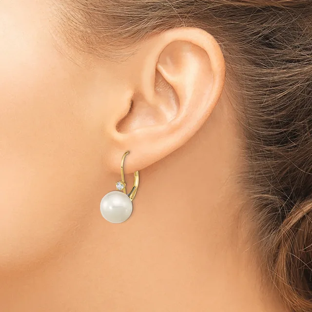 A person wearing gold hoop earrings with white pearl drops and small diamond accents, shown from the side profile of their ear and neck.