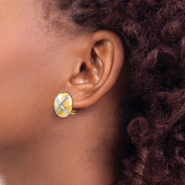 A person wearing a gold and silver crossover earring with a curved post, shown from the side view against their ear and neck.