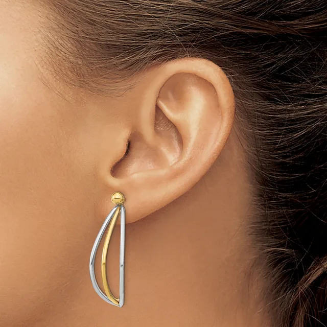 A teardrop-shaped earring with a two-tone design of silver and gold metal hanging from an earlobe.