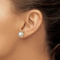 A woman wearing a round stud earring with a white pearl center surrounded by small diamonds in a silver setting.
