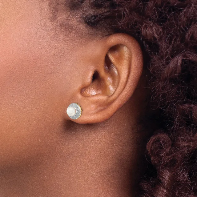 A person wearing a round stud earring with a white pearl center surrounded by a textured silver or diamond-set circular setting, shown from the side profile.