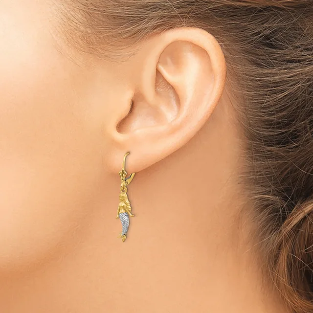A person wearing a gold-toned drop earring with textured details and a small diamond or crystal accent, shown from the side view of their ear.