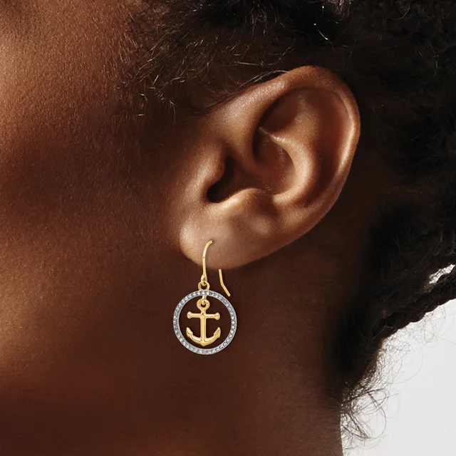Gold-toned anchor charm earring with diamond or crystal-set circular frame, hanging from a gold ear wire on a person's ear.