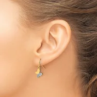 A person wearing a two-tone drop earring with a gold leaf-shaped component and a silver textured spherical stone, shown hanging from a fish hook ear wire.