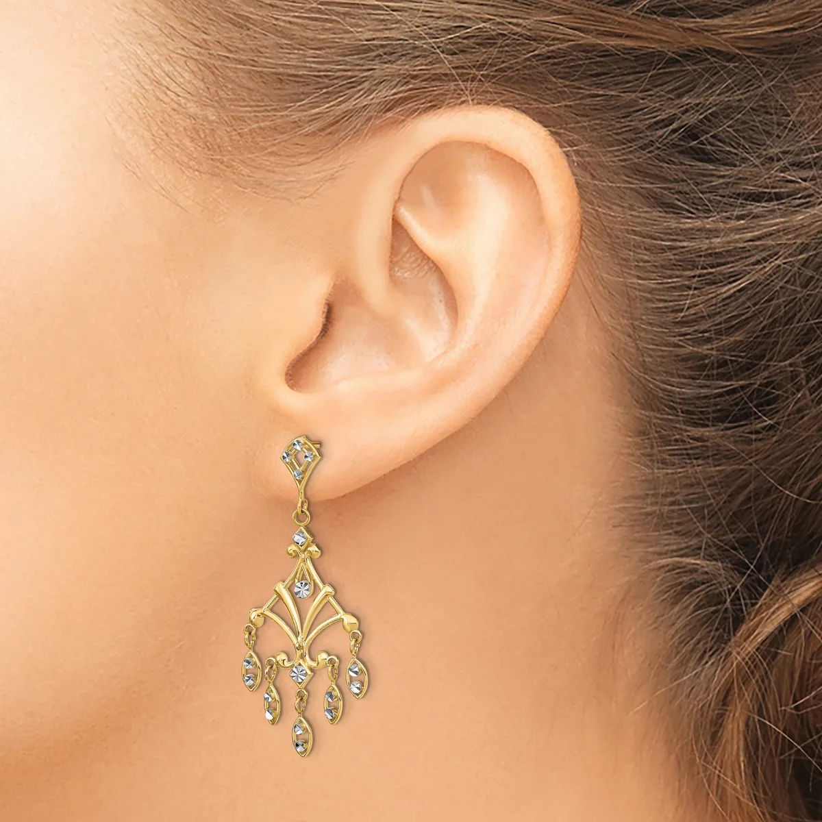 A gold chandelier-style earring with small round gemstones hangs from a stud, shown worn on a person's ear.
