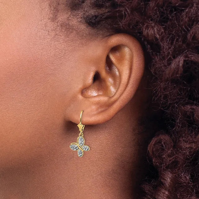 A person wearing a gold-toned floral cross earring with diamond or crystal accents, shown from the side view against their ear and shoulder.