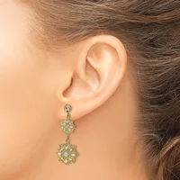 A woman wearing gold-toned floral drop earrings with clear crystal centers on both flowers, shown from the side profile of her ear and neck.