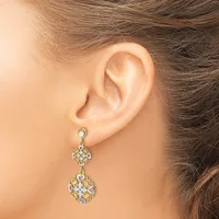 A woman wearing a two-tier dangle earring with ornate filigree design set with clear and yellow stones, shown from the side view of her ear.