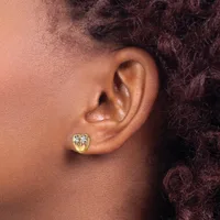 Close-up side view of a person's ear wearing a small gold heart-shaped stud earring with a clear gemstone center.