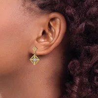 A person wearing a gold diamond-shaped drop earring with a small square stud, shown from the side profile against their neck and shoulder.