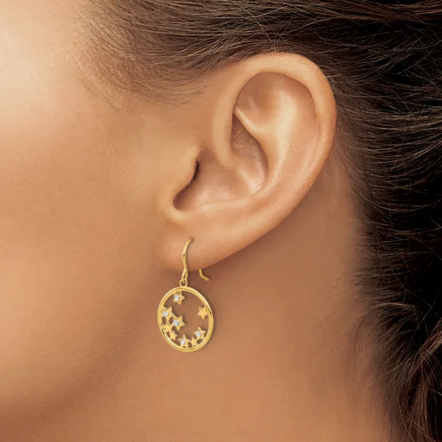 A woman wearing a gold teardrop-shaped earring with a cutout star pattern, shown from the side view of her ear and neck.