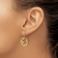 A woman wearing a gold teardrop-shaped earring with a cutout star pattern, shown from the side view of her ear and neck.