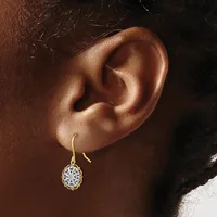 A person wearing a gold fishhook earring with a white filigree ball pendant hanging from their earlobe.