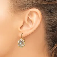 A person wearing a dangling earring with an oval pendant featuring a geometric sunburst design in two-tone metal, shown from the side view of their ear.