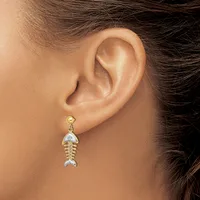 A person wearing a two-tone gold and silver fish-shaped dangle earring with a textured body and small stud post, shown on their earlobe from the side.
