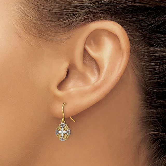 A person wearing a gold hook earring with a diamond and gemstone pendant drop on their left ear.