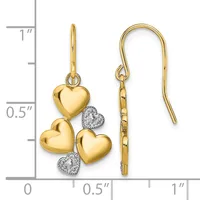 Gold heart-shaped earrings with diamond accents hanging from gold shepherd's hook ear wires, displayed against a measurement scale.