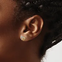 A person wearing a small gold heart-shaped earring with diamond accents in their pierced earlobe, shown in profile view.