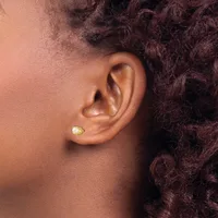 A close-up side view of a person's ear wearing a small gold stud earring with a yellow stone.