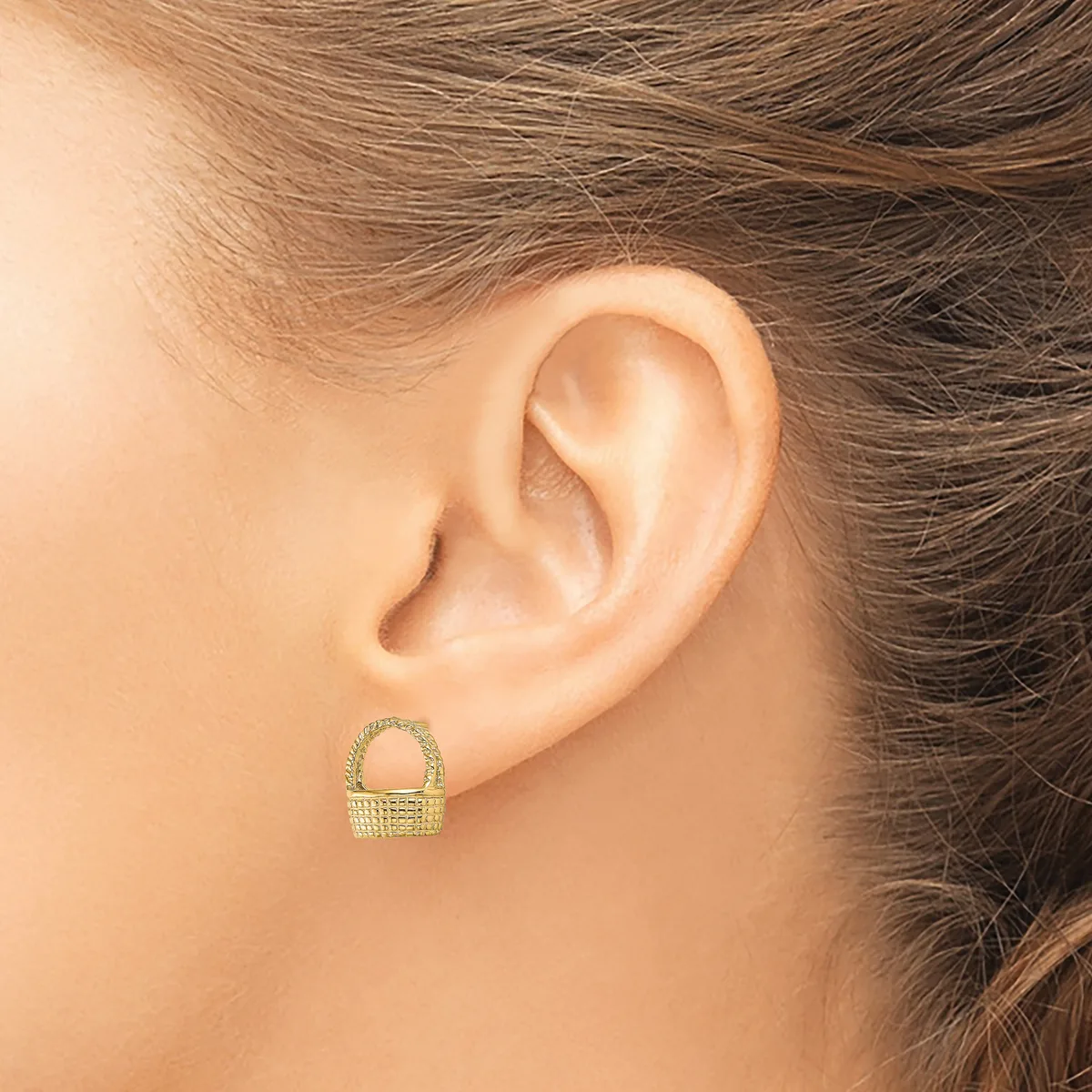 A small gold basket-shaped stud earring with textured surface worn on a person's earlobe, shown from the side profile.