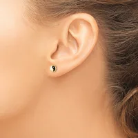 A person wearing a small silver stud earring with a yin-yang design in black and white, shown from the side profile of their ear.