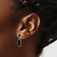 A person wearing a two-part dangling earring with a small round black stone stud on top and a rectangular black stone pendant below, both set in gold-toned metal.