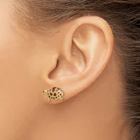 A gold turtle-shaped stud earring with dark enamel spots worn on a person's earlobe.