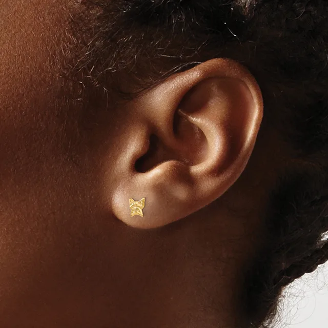 A small gold star-shaped stud earring in a pierced earlobe, shown in close-up profile view against warm brown skin.