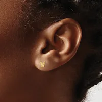 A small gold star-shaped stud earring in a pierced earlobe, shown in close-up profile view against warm brown skin.